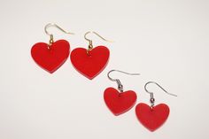 three red heart shaped earrings on white background