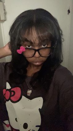 a woman with glasses and a hello kitty t - shirt is posing for the camera