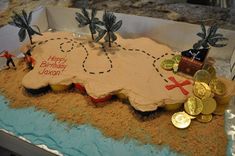 a birthday cake made to look like a pirate island with gold coins and palm trees