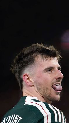 a man sticking his tongue out in front of the camera while wearing a green and white striped shirt