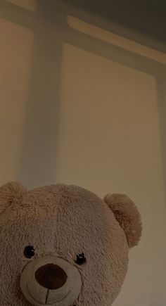 a brown teddy bear sitting on top of a white table next to a window with blinds