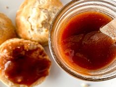 a glass jar filled with jam next to pastries