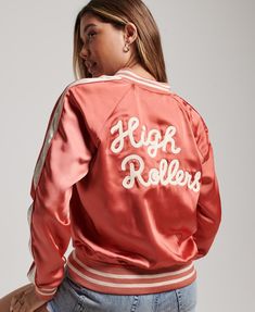 a woman wearing a pink satin jacket with high rollers written on the front and back