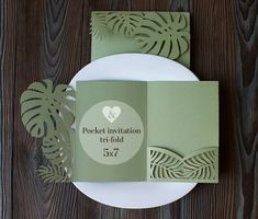 a green and white wedding stationery set on a wooden table with paper cutouts