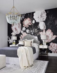 a bedroom decorated in black and white with flowers on the wall, chandelier