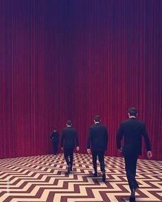 three men in suits are walking through a room with red curtained walls and floor