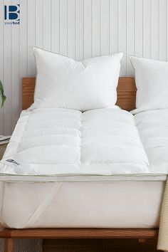 a bed with two pillows on top of it next to a plant and a potted plant