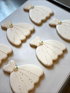 decorated cookies in the shape of wings on a baking sheet with green beads and bows