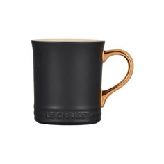 a black and gold mug with the word le cruiset on it