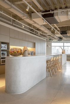 an empty kitchen and dining area in a modern office building with concrete countertops, white walls, and exposed ceiling lights