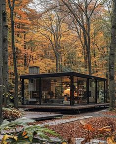 a small cabin in the woods surrounded by trees with yellow leaves on it's sides