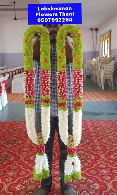 a man standing in front of a table with flowers and garlands on his head