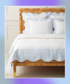 a bed with white linens and pillows on it, against a wooden headboard