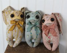 three stuffed animals sitting next to each other on top of a wooden table in front of a white wall