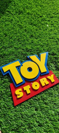 a toy story logo laying on top of green grass in the middle of a field