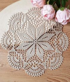 crocheted doily with pink flowers on wooden table