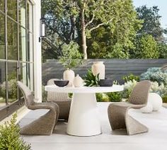 an outdoor dining area with chairs, table and potted plants