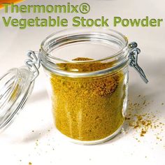 a glass jar filled with green powder next to an orange and white sign that says thermomix vegetable stock powder