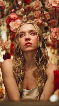 a woman with long hair sitting in front of flowers