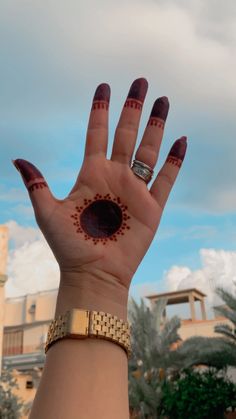 a woman's hand with red and gold designs on it, holding up her palm