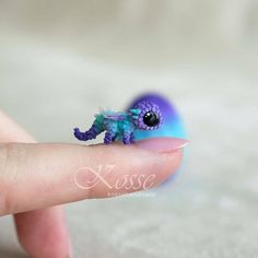 a tiny purple and blue toy sitting on top of a finger