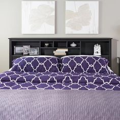 a bed with purple comforter and two pictures above it