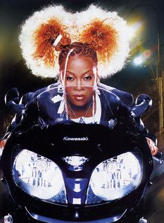 a woman sitting on top of a motorcycle with her hair in the middle of it