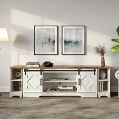 a living room scene with focus on the entertainment center and two framed pictures above it