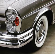 the front end of an old fashioned car with chrome rims and red brake lights