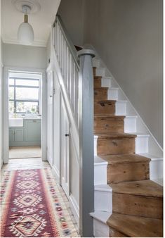 a staircase leading up to a kitchen and living room with an area rug on the floor