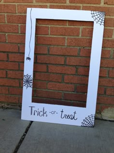 a trick - or - treat photo frame is on the sidewalk next to a brick wall