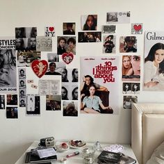 a white table topped with lots of pictures and other items next to a wall covered in posters