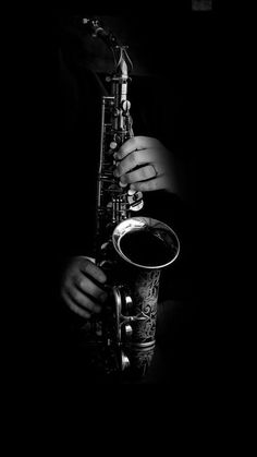 black and white photograph of a man playing a saxophone in the dark with his hands