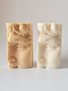 two candles with faces on them sitting next to each other in front of a white background