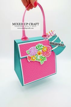 a hand is holding a pink and blue bag with flowers on the handle, while it has