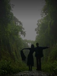 two people standing in the middle of a forest with their arms spread out to each other