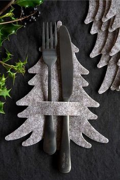 a fork and knife sitting on top of a table next to christmas tree shaped napkins