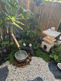 a small garden with rocks, plants and a water feature in the center is lit by a lantern