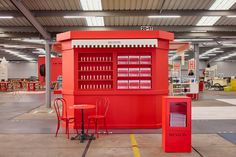 a red kiosk sitting inside of a building next to two tables and chairs