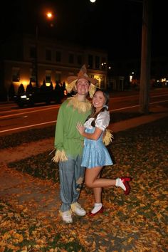 a man and woman dressed up in costumes posing for a photo on the street at night