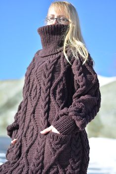 a woman wearing a sweater and glasses standing in the snow