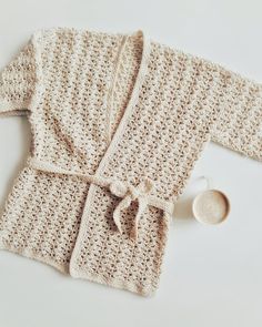 a crocheted robe and spoon on a white surface