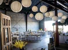 a room filled with lots of tables covered in white paper lanterns