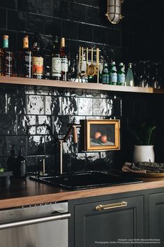 a kitchen with black tiles and wooden counter tops, gold trimming on the backsplash