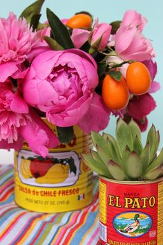 pink flowers and oranges are in tin cans