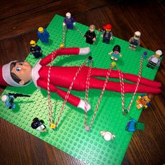 a lego elf laying on top of a green mat next to toys and candy canes