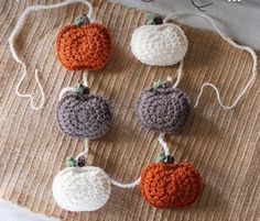 four crocheted pumpkins are hanging on a piece of burlocked fabric