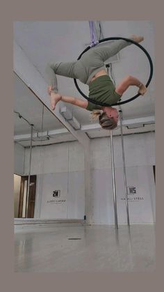 a man is doing tricks on a pole with a hoop in an empty room,