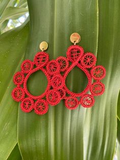 red crochet earrings on top of a green leafy plant in the sun