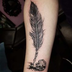 a black and white tattoo with a feather on the arm, next to a crystal